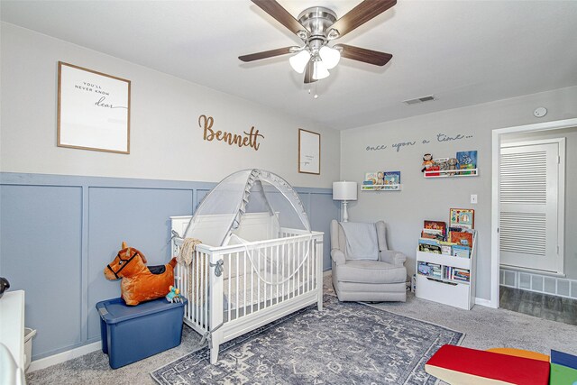 carpeted bedroom featuring ceiling fan, baseboards, visible vents, and a nursery area