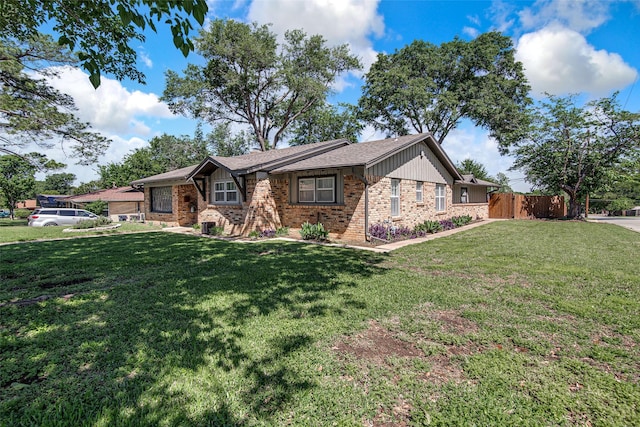 view of front of property featuring brick siding, a front lawn, and fence
