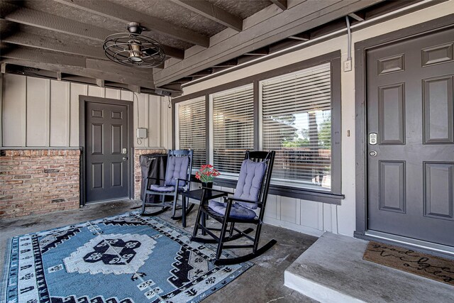 property entrance with board and batten siding, a ceiling fan, and brick siding