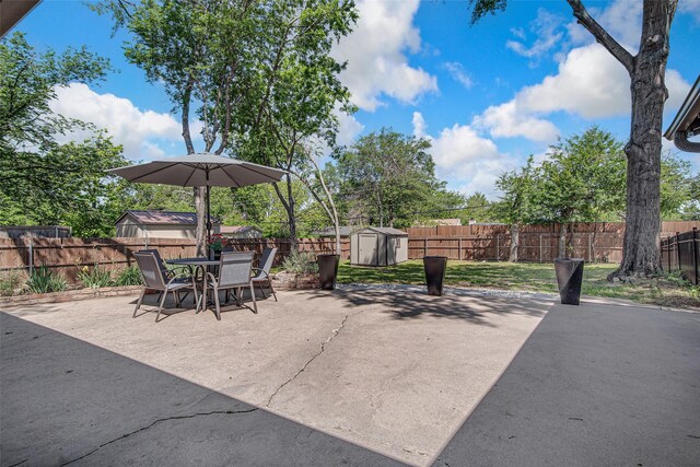 view of patio / terrace with a fenced backyard, an outdoor structure, a storage shed, and outdoor dining area