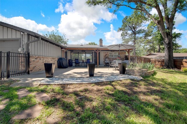 rear view of house with a chimney, board and batten siding, fence, a patio, and brick siding