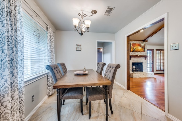 2307 Castle Rock Rd, Carrollton, TX 75007 - dining room featuring a chandelier, a fireplace, light tile patterned flooring, baseboards, and crown molding