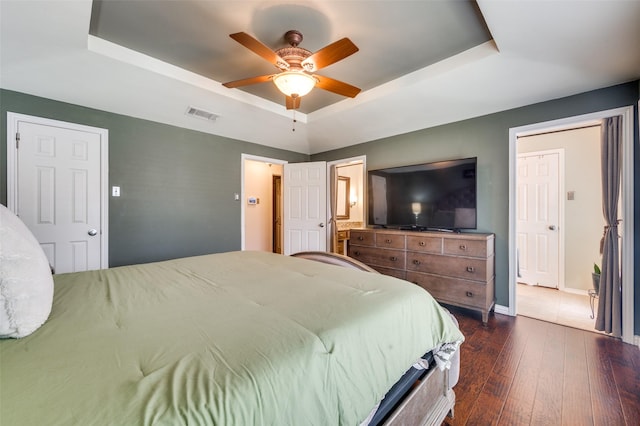 2307 Castle Rock Rd, Carrollton, TX 75007 - bedroom featuring a tray ceiling, dark wood finished floors, baseboards, ceiling fan, and ensuite bath