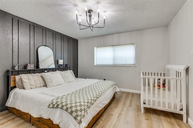 bedroom featuring baseboards, a notable chandelier, wood finished floors, and a textured ceiling