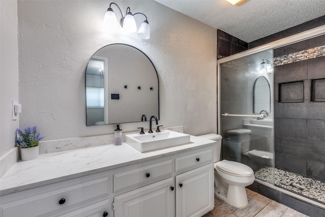bathroom with vanity, a textured ceiling, a shower stall, and toilet
