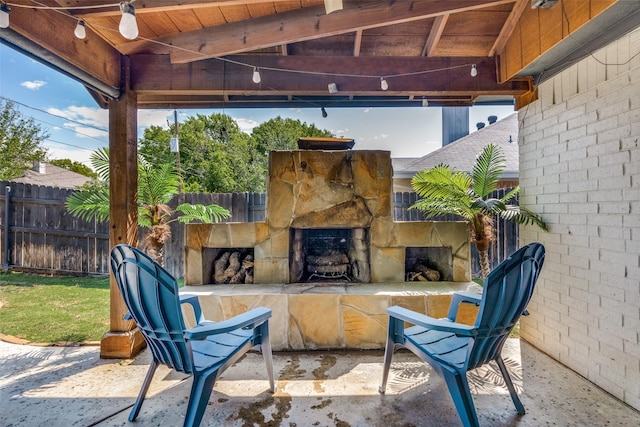 view of patio with fence and an outdoor stone fireplace