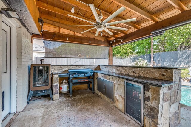 view of patio / terrace featuring beverage cooler, an outdoor kitchen, a ceiling fan, and fence