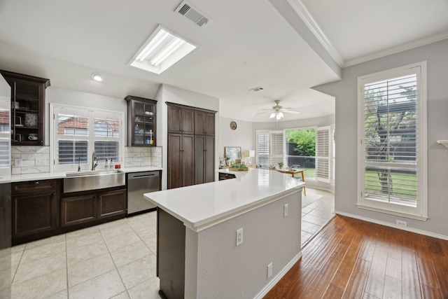 kitchen featuring stainless steel dishwasher, a sink, tasteful backsplash, visible vents, and light countertops