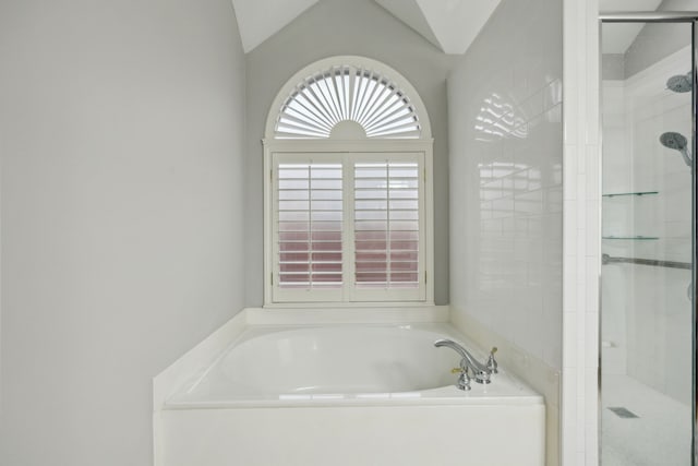 full bathroom featuring a stall shower, a bath, and vaulted ceiling