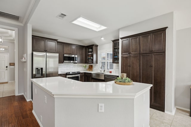 kitchen featuring dark brown cabinets, visible vents, appliances with stainless steel finishes, and tasteful backsplash