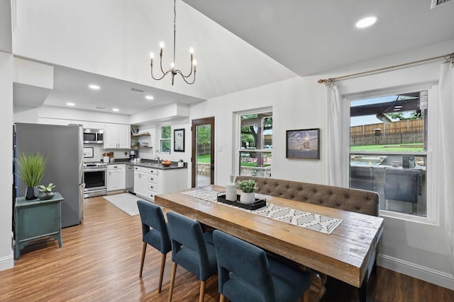 dining room featuring an inviting chandelier, visible vents, baseboards, light wood finished floors, and vaulted ceiling