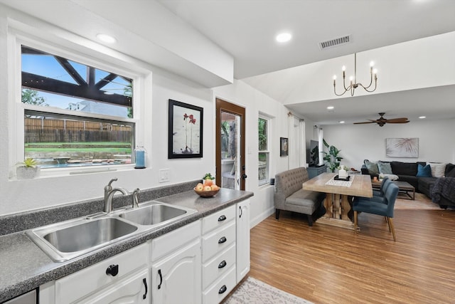 kitchen with dark countertops, a sink, light wood-style flooring, open floor plan, and a wealth of natural light