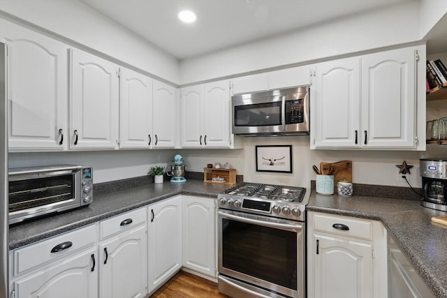 kitchen featuring stainless steel appliances, dark countertops, white cabinetry, and a toaster