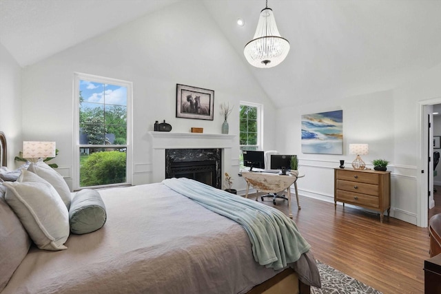bedroom featuring wood finished floors, multiple windows, a premium fireplace, and high vaulted ceiling