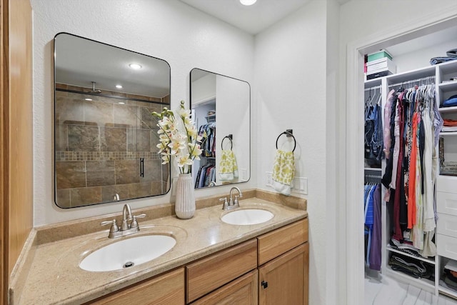 full bathroom featuring double vanity, a sink, a walk in closet, and a stall shower