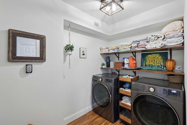 washroom featuring washer and dryer, laundry area, baseboards, wood finished floors, and visible vents