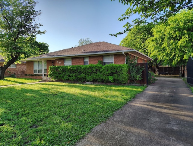 view of side of home featuring a lawn, brick siding, driveway, and fence