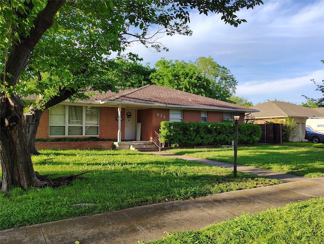 ranch-style home with brick siding, a front lawn, and fence