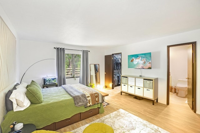 bedroom with light wood-type flooring, a closet, and connected bathroom