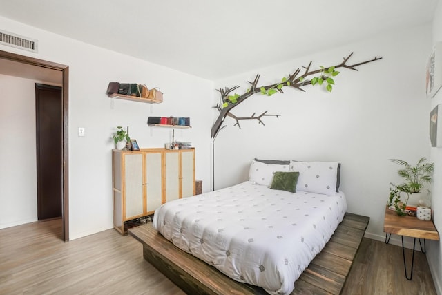 bedroom with visible vents, wood finished floors, and baseboards
