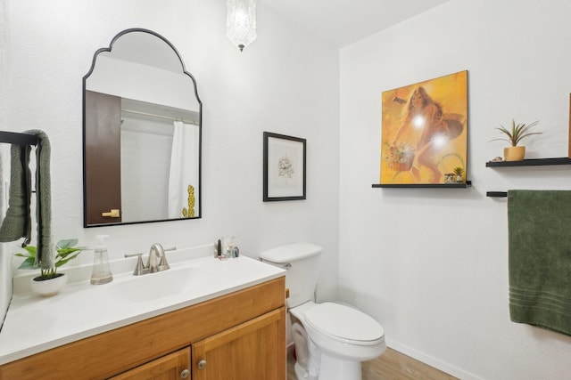 bathroom featuring toilet, vanity, wood finished floors, and baseboards