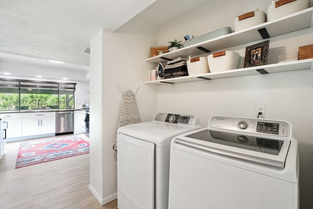 laundry room featuring light wood-type flooring, laundry area, a sink, and separate washer and dryer