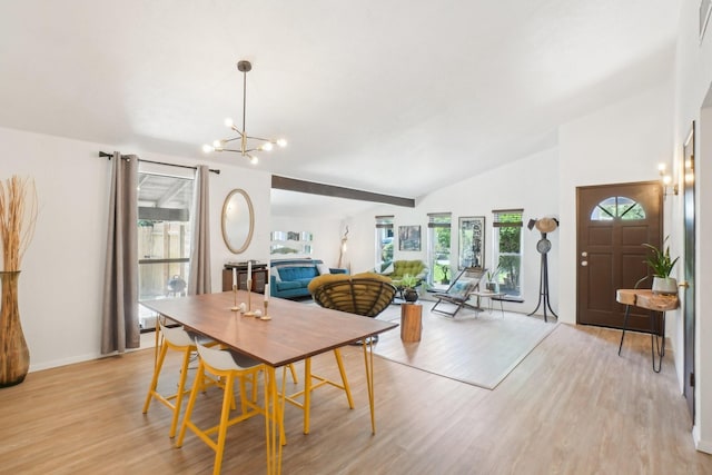dining space featuring light wood finished floors, vaulted ceiling, baseboards, and a notable chandelier