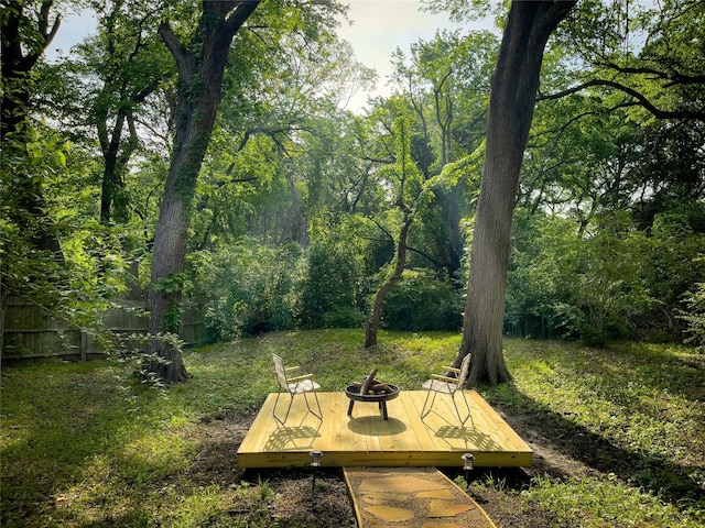 view of yard featuring fence, a forest view, and a wooden deck