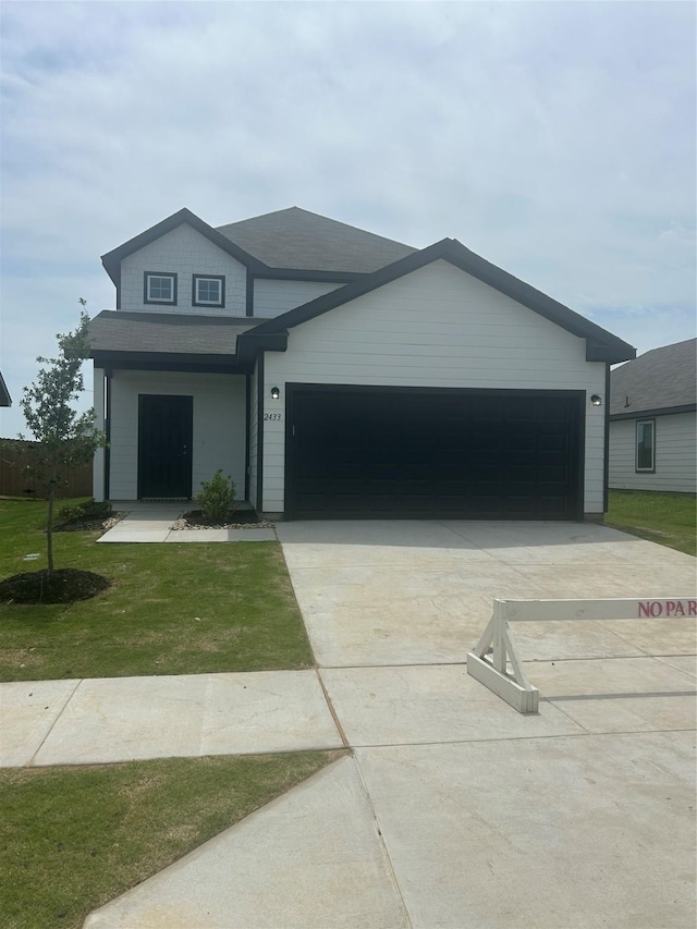 view of front of home featuring a garage, roof with shingles, a front lawn, and concrete driveway