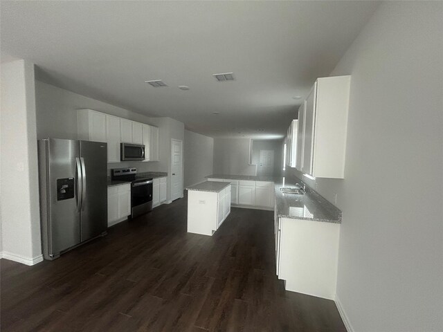 kitchen with stainless steel appliances, visible vents, dark wood-type flooring, and light stone counters