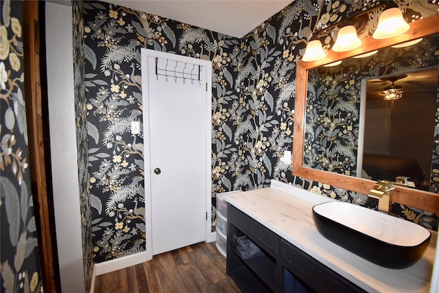 bathroom featuring wallpapered walls, wood finished floors, vanity, and ceiling fan