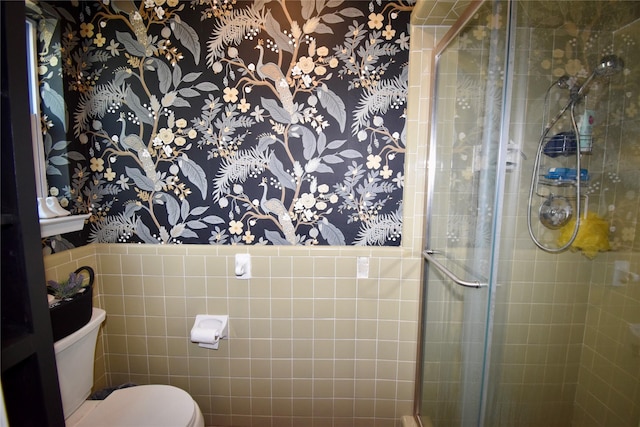 bathroom with wallpapered walls, toilet, and a stall shower