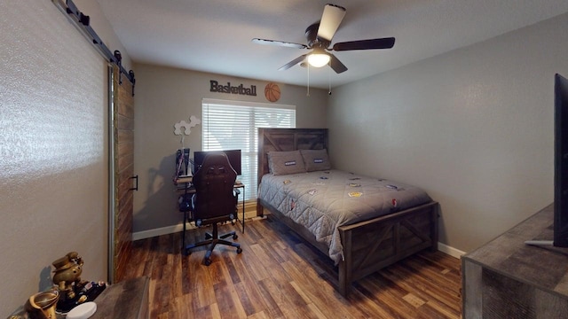 bedroom featuring baseboards, a ceiling fan, wood finished floors, and a barn door