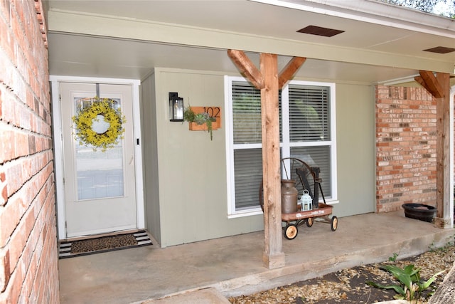 entrance to property featuring brick siding and visible vents