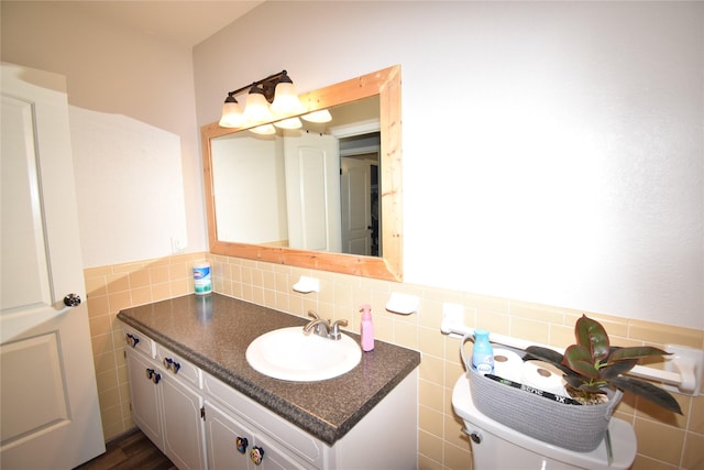 half bathroom featuring tile walls, vanity, and toilet