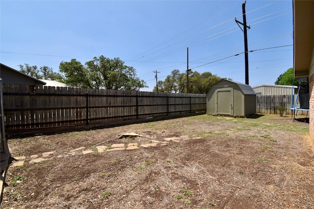 view of yard featuring a storage unit, an outdoor structure, a fenced backyard, and a trampoline
