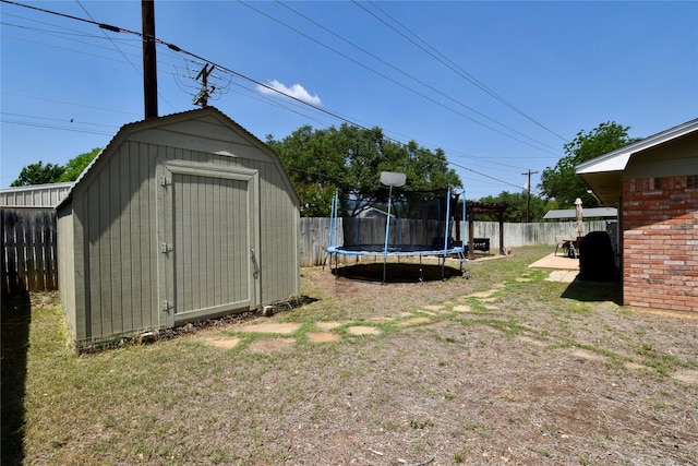 exterior space featuring a storage shed, a trampoline, a fenced backyard, and an outdoor structure