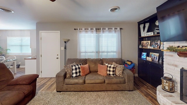 living room with wood finished floors, visible vents, and ceiling fan