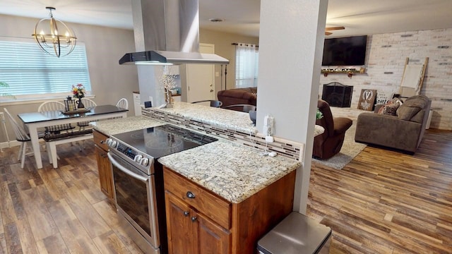 kitchen featuring wood finished floors, plenty of natural light, brown cabinetry, open floor plan, and stainless steel electric range oven