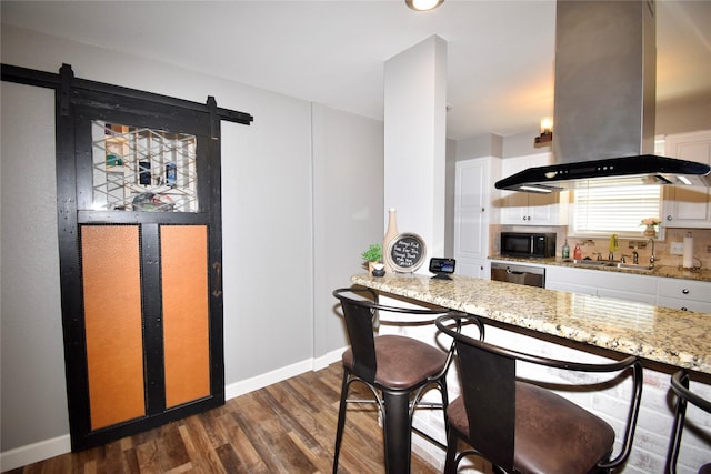 kitchen with island exhaust hood, light stone counters, a sink, dark wood-style flooring, and white cabinetry
