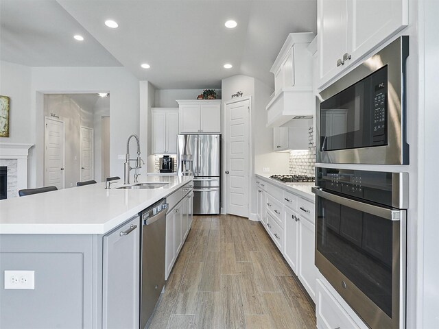 kitchen with a sink, white cabinetry, light countertops, appliances with stainless steel finishes, and recessed lighting