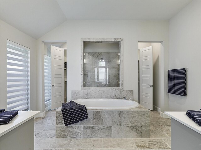full bath featuring marble finish floor, vaulted ceiling, vanity, a bath, and a stall shower