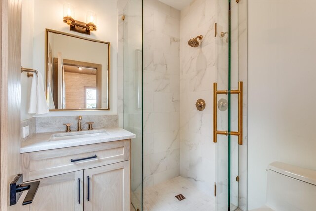bathroom with a marble finish shower, vanity, and toilet