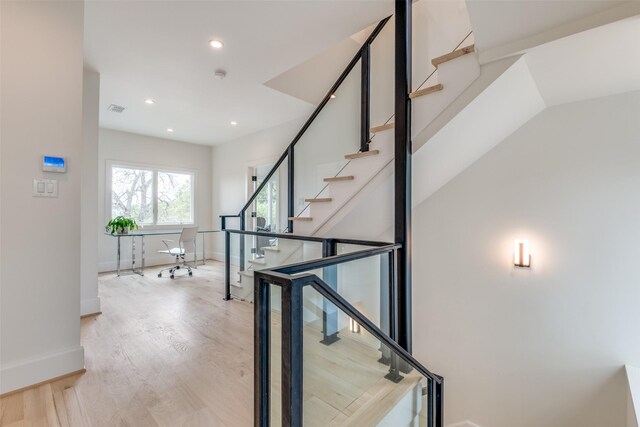 staircase featuring baseboards, wood finished floors, and recessed lighting