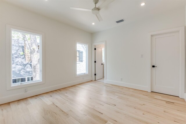 spare room with wood finished floors, visible vents, a wealth of natural light, and ceiling fan