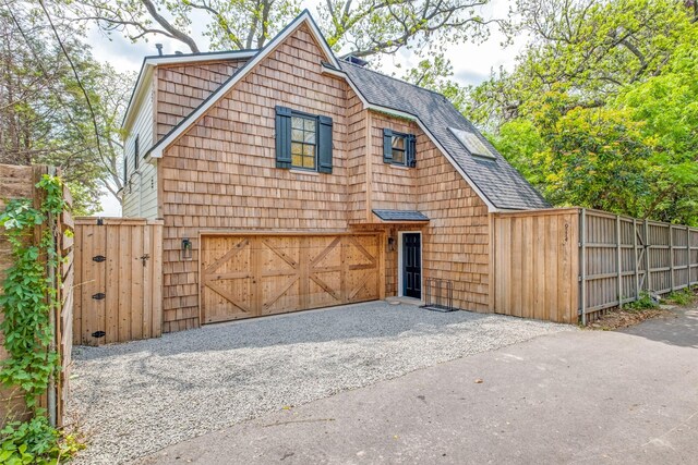 view of front of property featuring an attached garage, roof with shingles, fence, and driveway