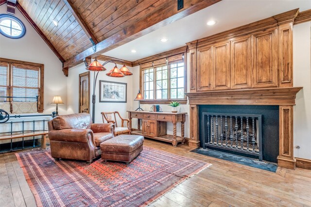 living area featuring hardwood / wood-style floors, lofted ceiling with beams, wooden ceiling, and a fireplace with flush hearth