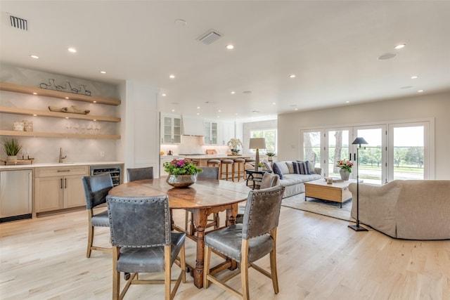 dining space featuring recessed lighting, wet bar, light wood-style flooring, and visible vents