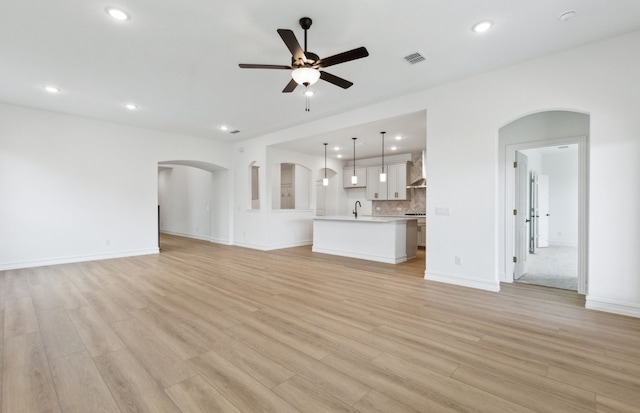 11205 Boyne Ave, Fort Worth, TX 76052 - unfurnished living room featuring arched walkways, a ceiling fan, light wood-style floors, a sink, and recessed lighting
