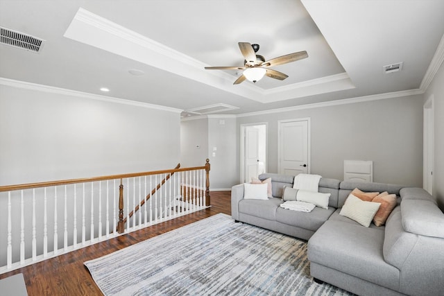 living room with attic access, visible vents, ceiling fan, and a tray ceiling